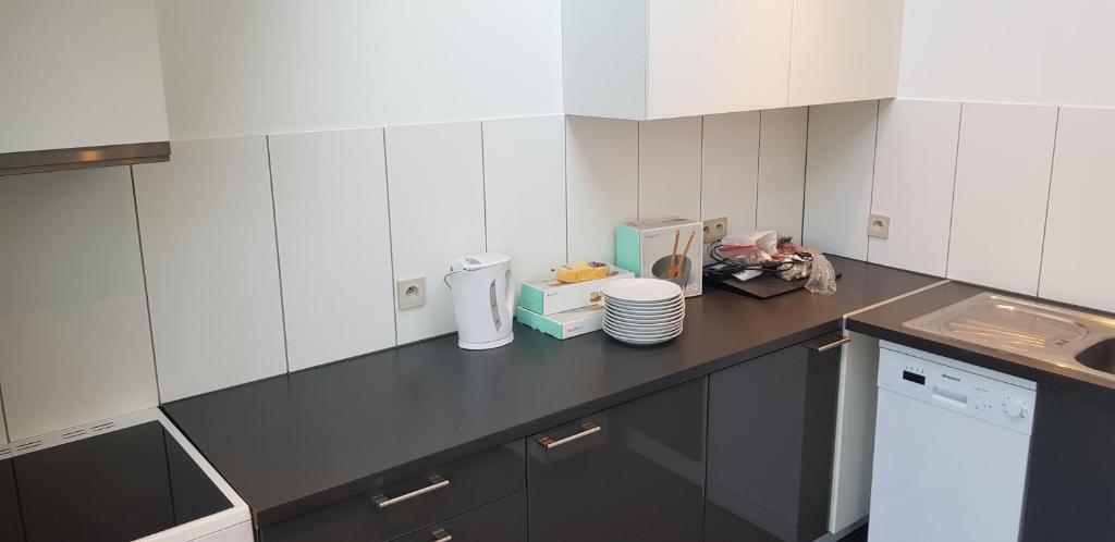 a kitchen with white cabinets and a black counter top at Lavan in Leuven