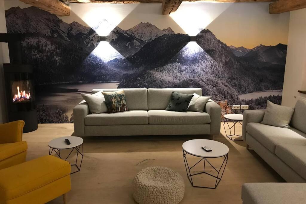 a living room with a couch and a mountain mural at Ferienhaus Lieblingsplatz-Füssen - stilvoll urlauben & wohnen in Füssen