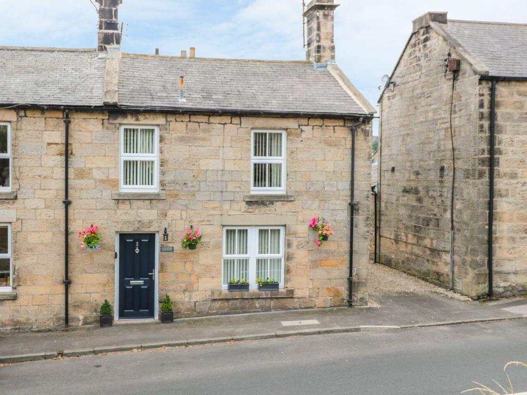 an old stone house with a blue door on a street at Cooper's Cottage in Morpeth