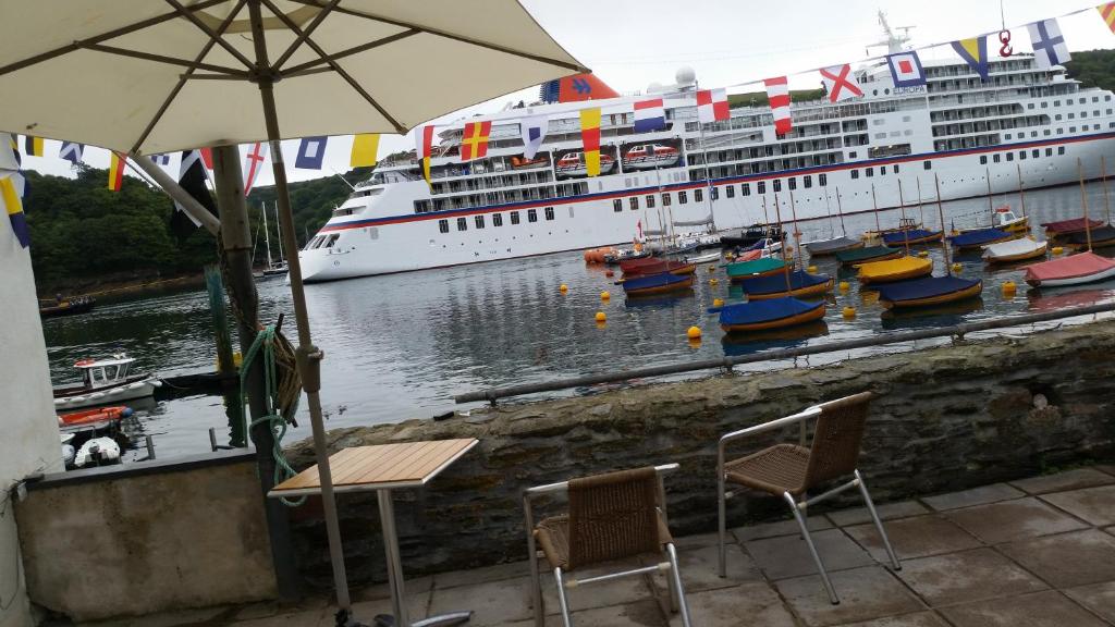 a cruise ship docked at a dock with chairs and an umbrella at Reed's of Fowey in Fowey