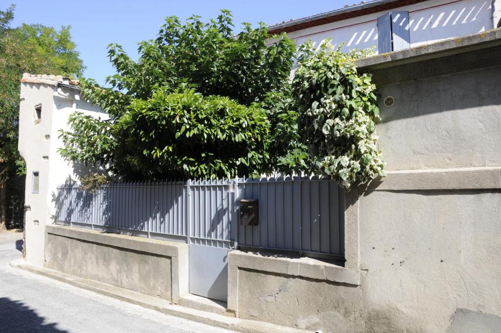 a fence with a gate with a tree on it at La Petite Maison in Cesseras