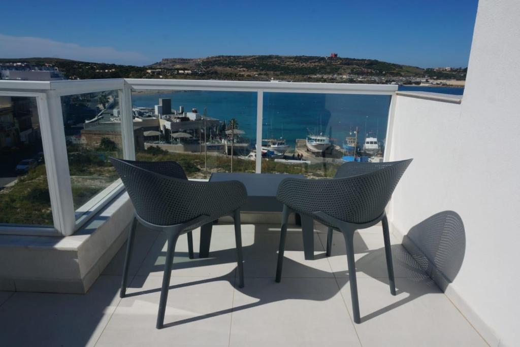 a table and chairs on a balcony with a view of the ocean at Sea View Penthouse Mellieha Bay in Mellieħa