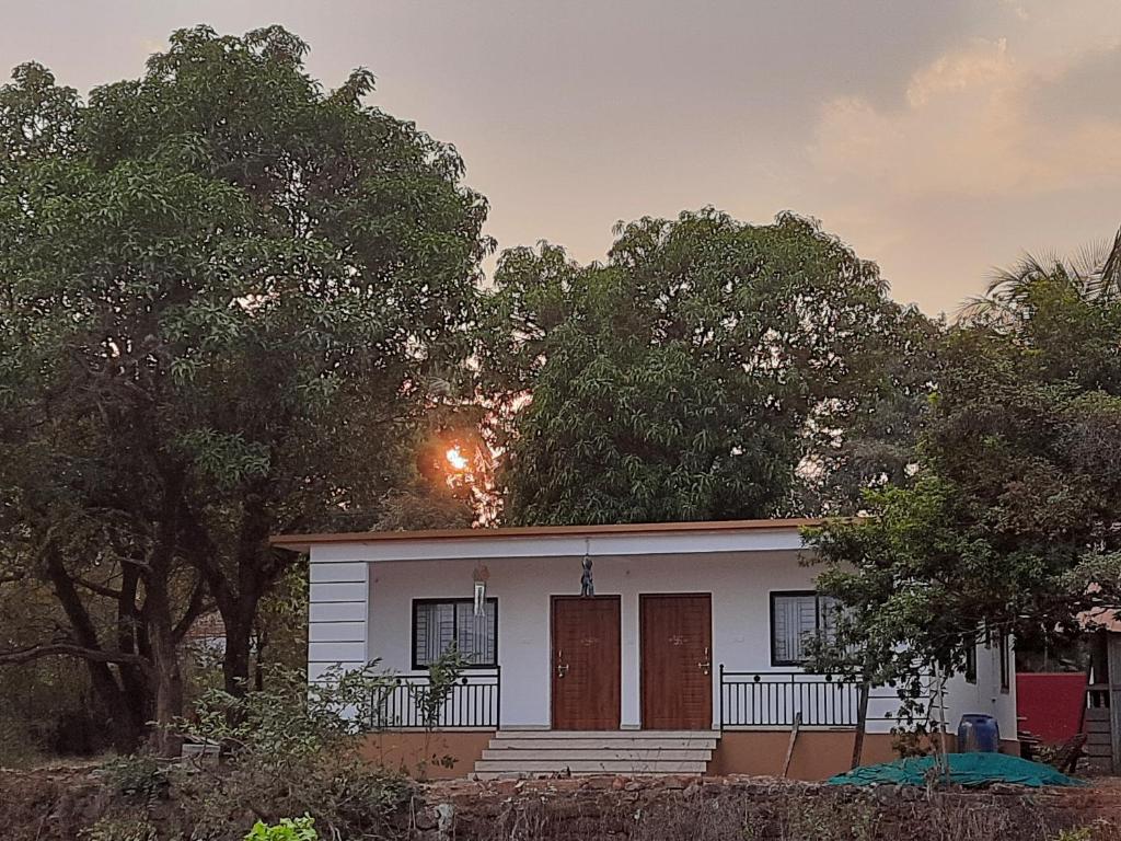 uma pequena casa branca com árvores em frente em Jiten Homestay em Anjuna