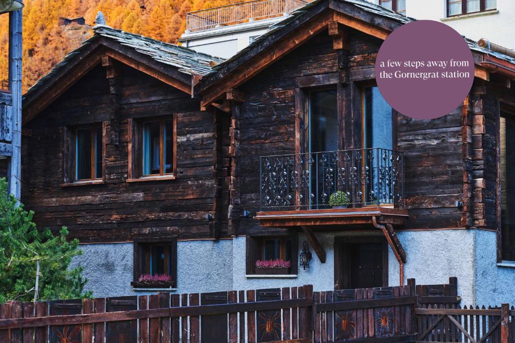 a wooden house with a balcony and a sign at SCHLOSS Cottage - A Swiss Experience in Zermatt