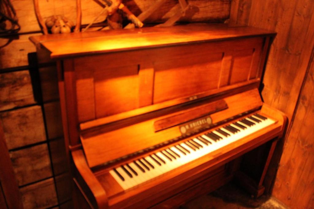 an old wooden piano sitting in a room at Ålbyggården in Røros