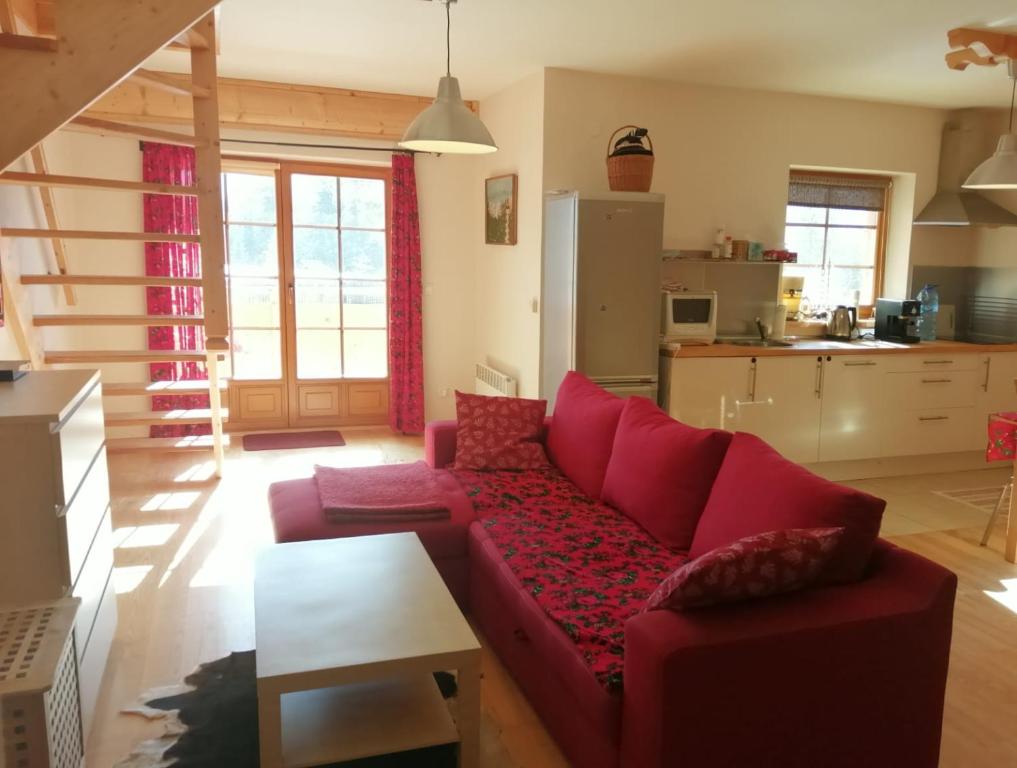 a living room with a red couch and a kitchen at Apartament Markówka w Kościelisku in Kościelisko