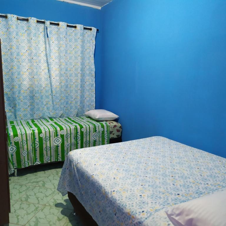 a blue room with two beds and a curtain at Quarto Duplo Confort in Barueri