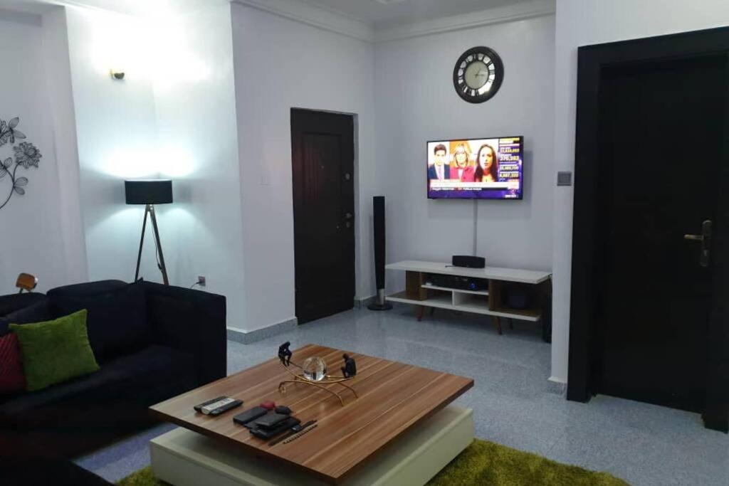 uma sala de estar com um sofá, uma mesa e uma televisão em Well furnished and spacious 2 bedroom apartment em Abuja