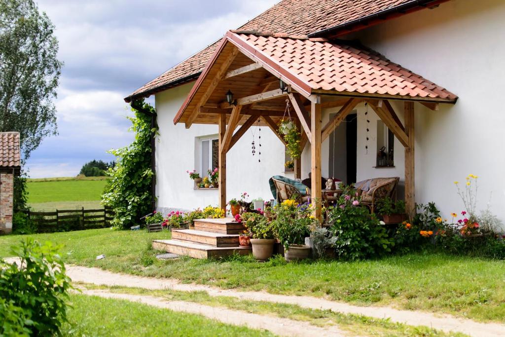 une maison blanche avec une pergola en bois dans l'établissement Zakątek Szczęścia, à Kiwity