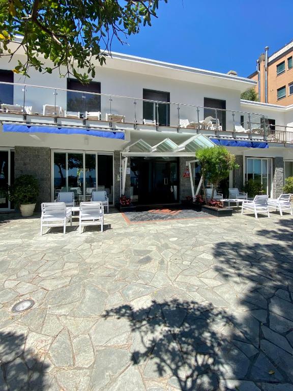un edificio con sedie bianche e un patio di Piccolo hotel le Palme a San Bartolomeo al Mare