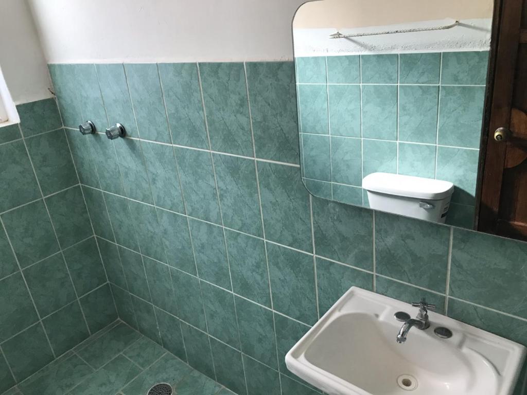 un bagno piastrellato verde con lavandino e specchio di Hotel Izala a San Pedro Pochutla