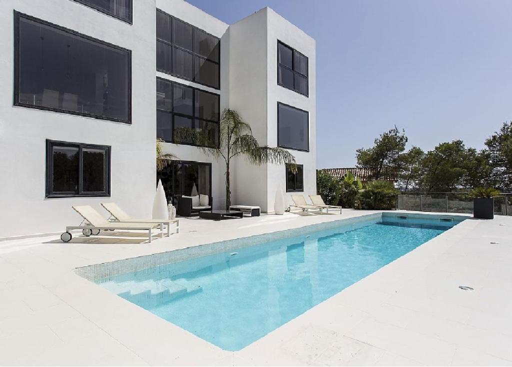 uma casa com piscina ao lado de um edifício em Architect modern design villa in Sitges Hills em Olivella