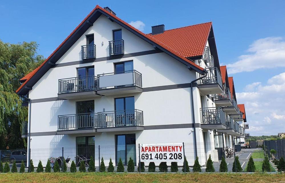 un gran edificio blanco con un cartel. en Apartamenty Majer Łeba, en Łeba