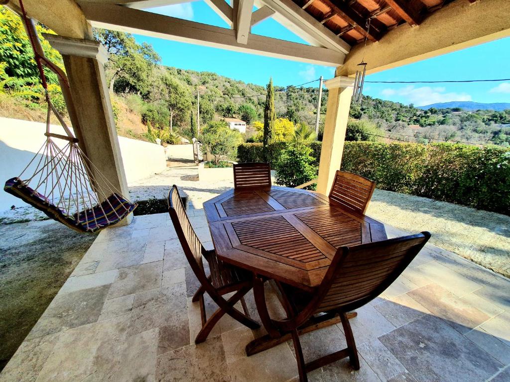 een houten tafel en stoelen op een patio met een schommel bij Petit Paradis in Collobrières