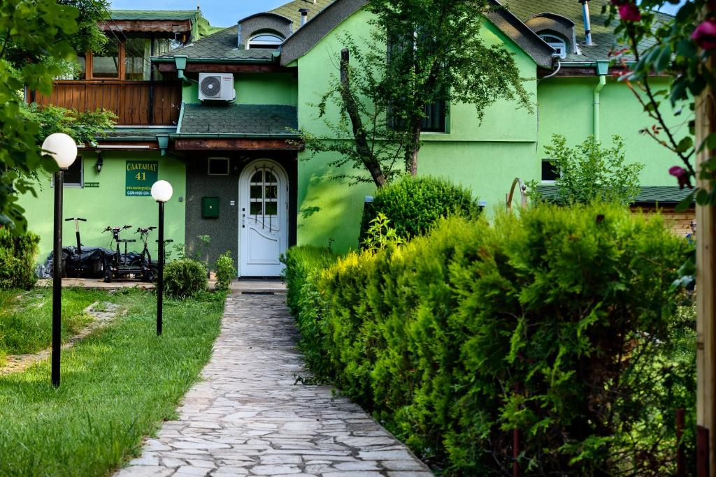 a green house with a white door and a path at Vila Saltanat 41 in Varna City