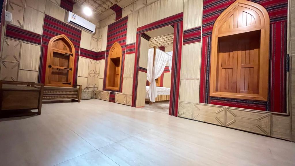 een lege kamer met een houten deur en een kamer met een bed bij Fort Guesthouse نُزل القلعة in Muscat