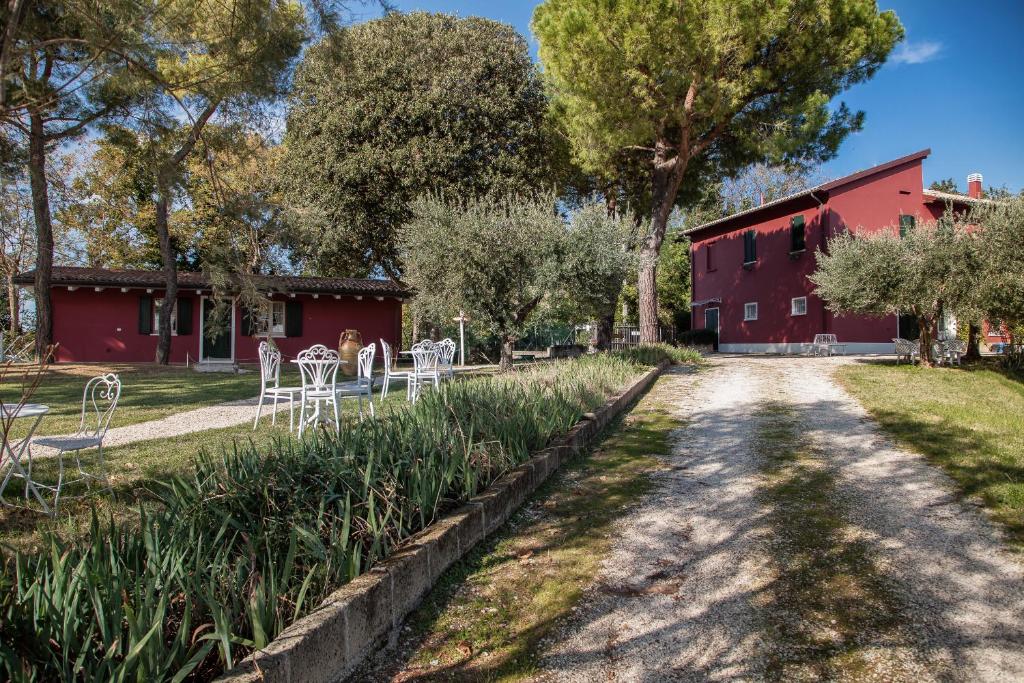 un chemin de terre devant un bâtiment rouge dans l'établissement Agriturismo Ca' Verde - il giardino narrante, à Fiorenzuola di Focara