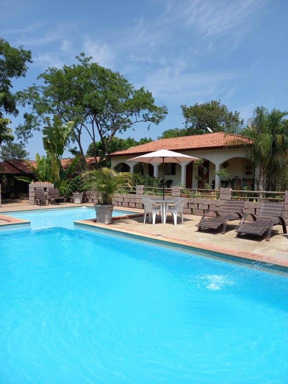 une piscine avec des chaises et une maison en arrière-plan dans l'établissement Recanto Pousada Sonho Meu, à Analândia