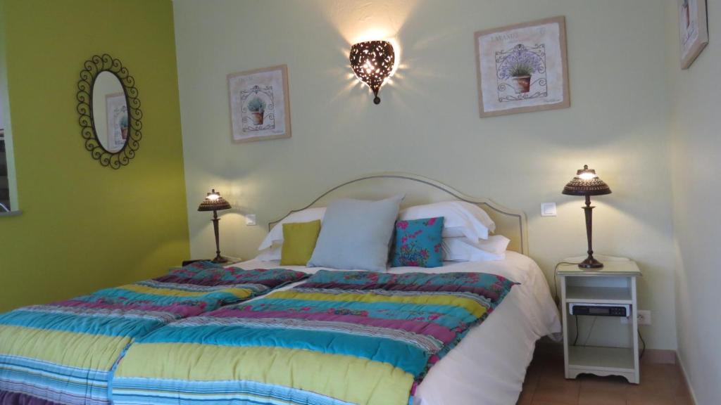 a bedroom with a bed with a colorful comforter at La Résidence du Moulin in Tourrettes-sur-Loup