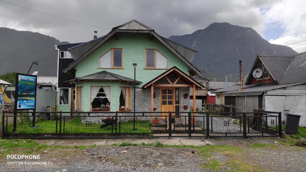 ein grünes Haus mit einem Berg im Hintergrund in der Unterkunft Paraiso Patagonico in Chaitén