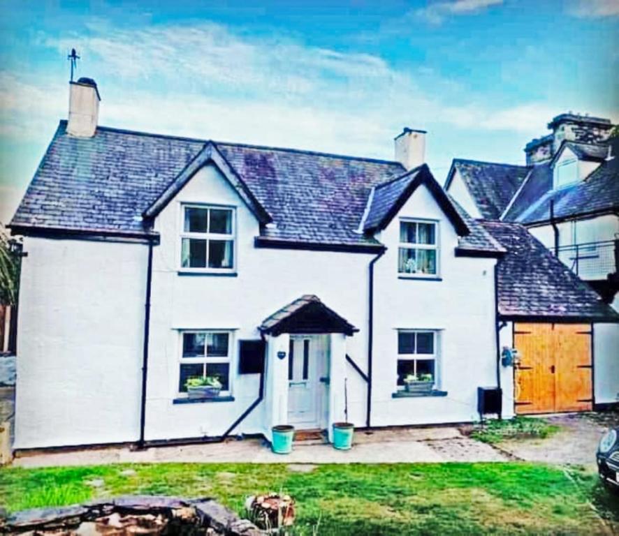 a white house with a brown door at The Old Smithy in Trefriw