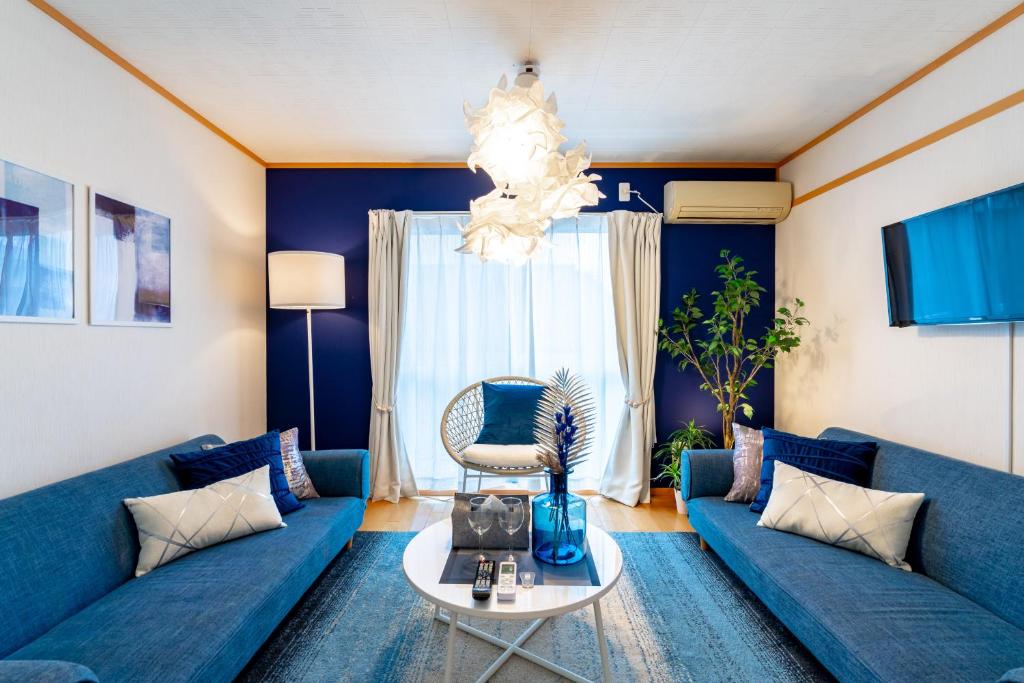 ein Wohnzimmer mit blauen Sofas und einem Tisch in der Unterkunft Type B Room 40平米 -ウル エスポワール那覇- in Naha