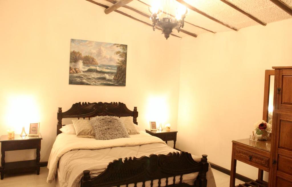 1 dormitorio con 1 cama y una pintura en la pared en Casa de hospedaje Vivaio, en Paipa
