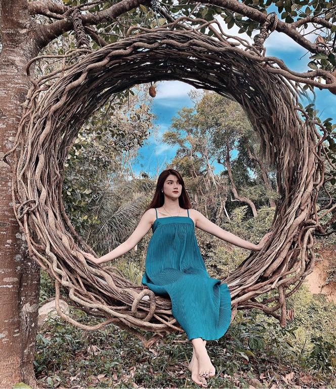 a woman in a blue dress is sitting in a wreathedigun at Homestay De la Rosa - Côn Đảo in Con Dao