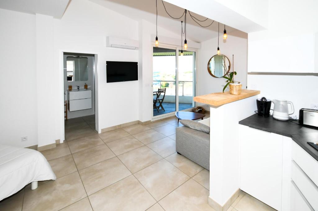 a kitchen and living room with white walls and tile floors at Le Château Leenhardt in Le Grau-du-Roi