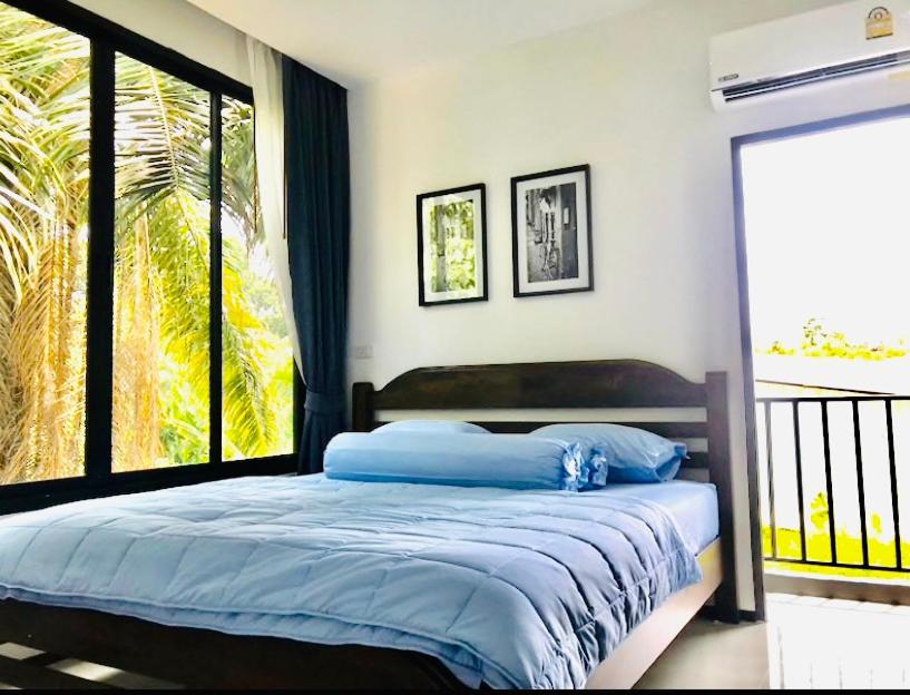 um quarto com uma cama com lençóis azuis e uma janela em The Best Room@Thalang2 em Thalang