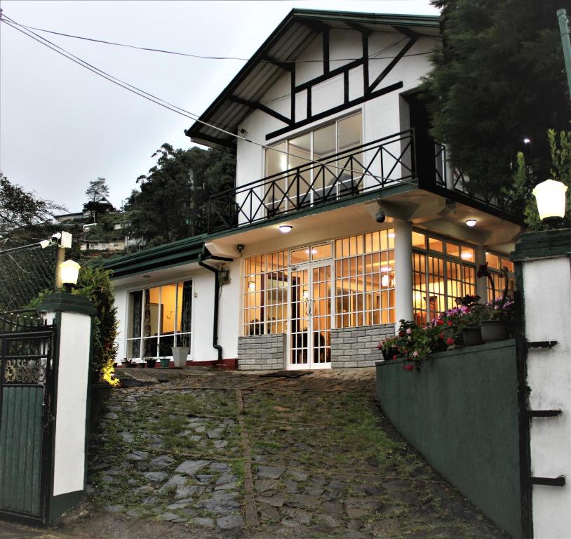 a white house with a gate and a porch at Blossomwell Bungalow in Nuwara Eliya