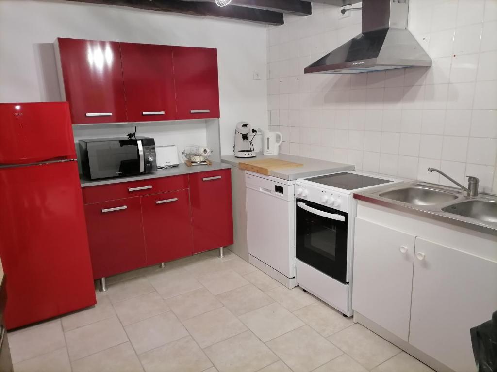 a kitchen with red cabinets and a sink and a microwave at Gîtes aux cœurs des vignes a 10mm du zoo de beauval 3 étoiles in Mareuil-sur-Cher