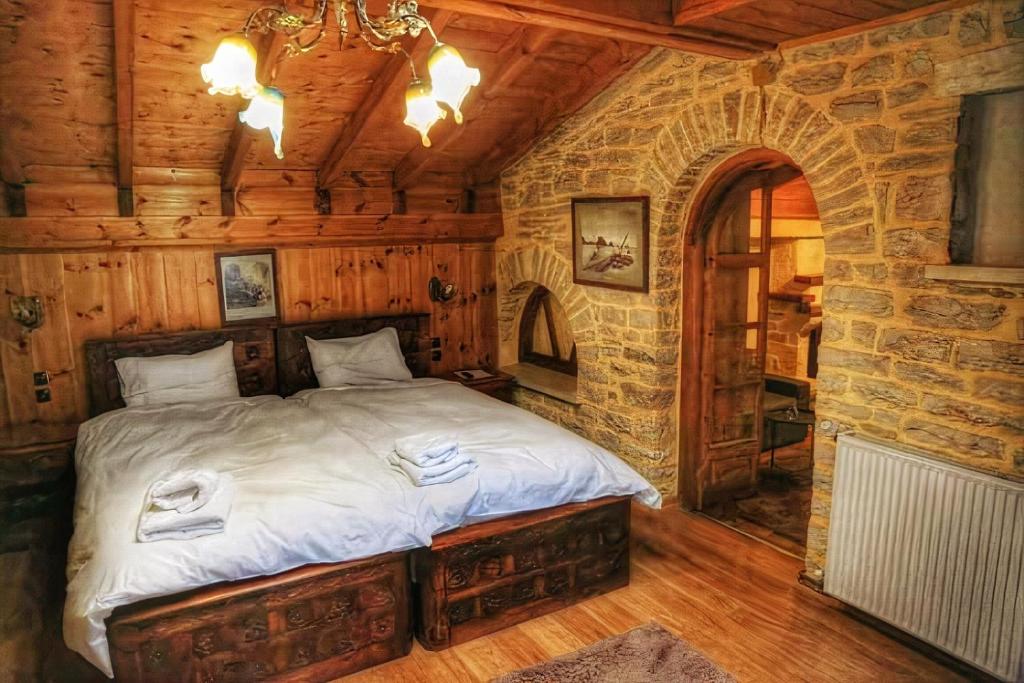 1 dormitorio con 1 cama en una habitación con una pared de piedra en Archontiko Zarkada, en Monodendri