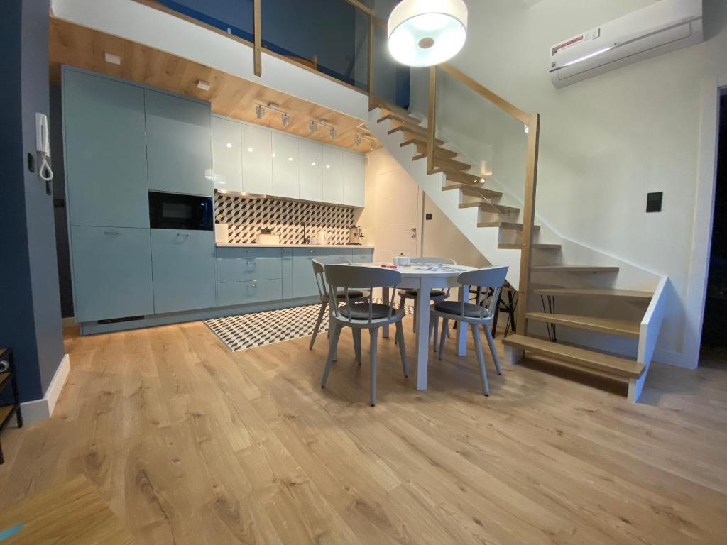 a kitchen and dining room with a table and a staircase at APARTAMENT KRYNICA MORSKA in Krynica Morska