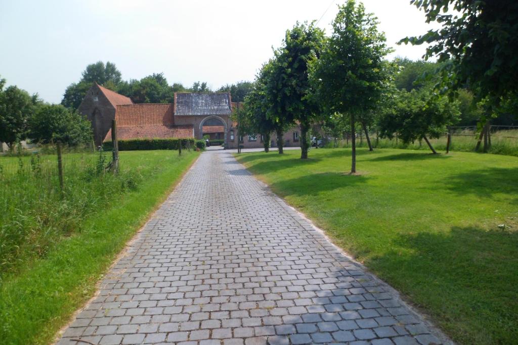 um caminho de paralelepípedos num parque com um edifício em Gîte de la Noyelle à Sainghin en Mélantois em Sainghin-en-Mélantois