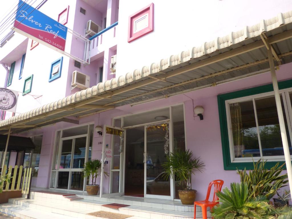 um edifício cor-de-rosa com uma cadeira vermelha à frente. em Silver Reef em Udon Thani