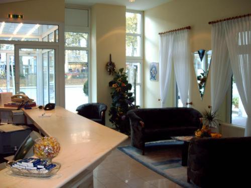 sala de estar con mesa, sillas y ventanas en Hotel Antares, en Oldenburg