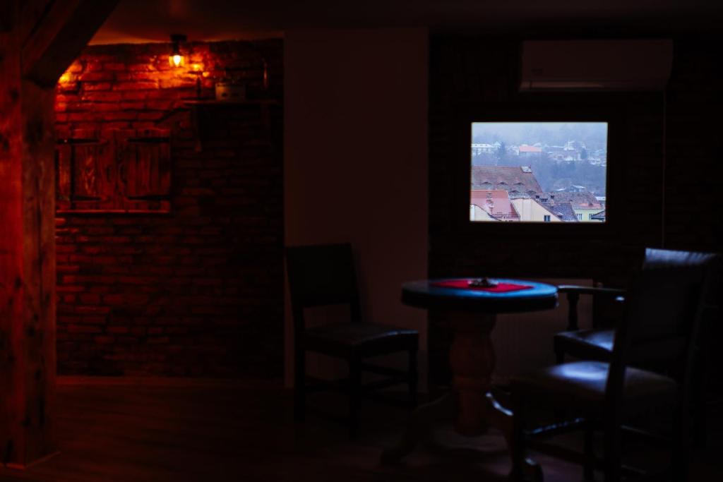 um quarto escuro com uma mesa e cadeiras e uma televisão em Casa Moldo em Sighisoara
