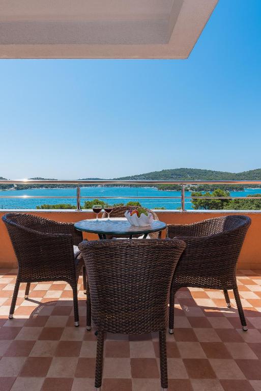 a table and chairs on a patio with a view of the water at Apartments Hari Tisno in Tisno