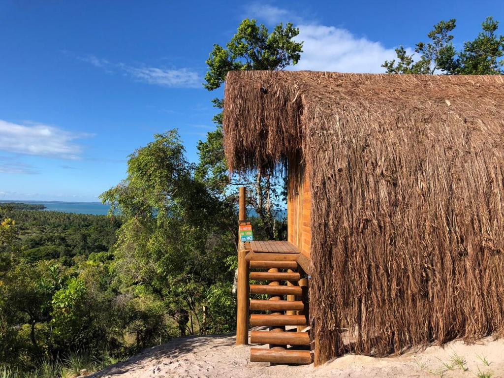 eine kleine Hütte mit einem Strohdach und einer Treppe in der Unterkunft Nature Moreré - Bangalôs com vista para o Mar in Moreré