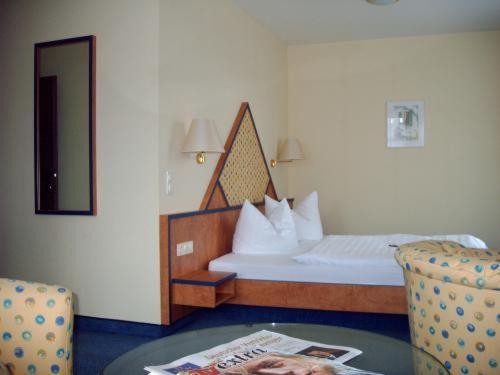 a bedroom with a bed and a table and a chair at Hotel Alexander in Oldenburg