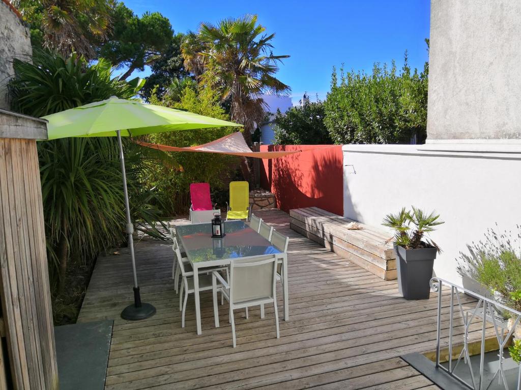 a patio with a table and chairs and an umbrella at Maison de ville Royan centre - Meublé tourisme 4 étoiles in Royan