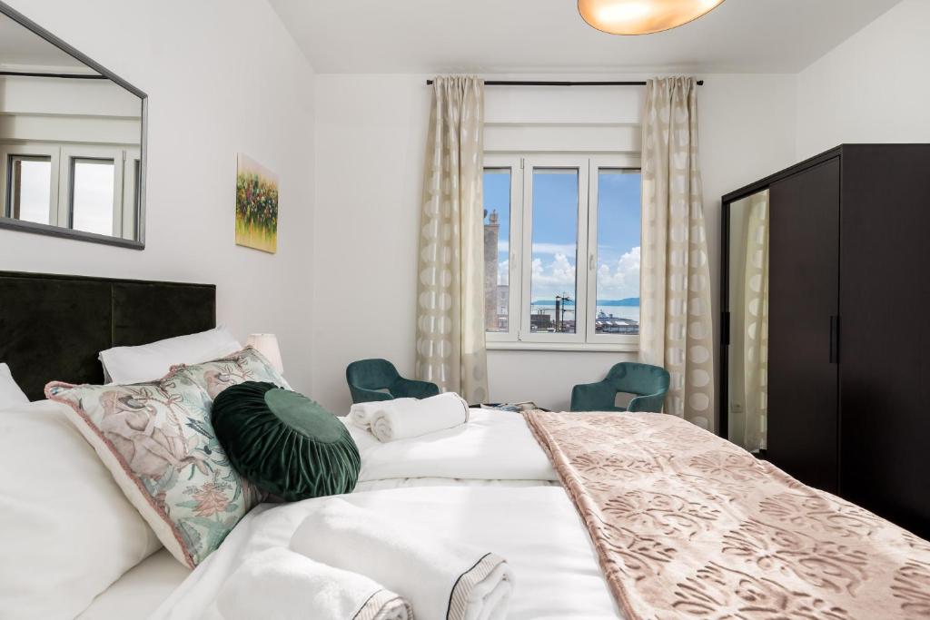 Schlafzimmer mit einem Bett mit weißer Bettwäsche und Kissen in der Unterkunft Apartman Altamar Rijeka in Rijeka