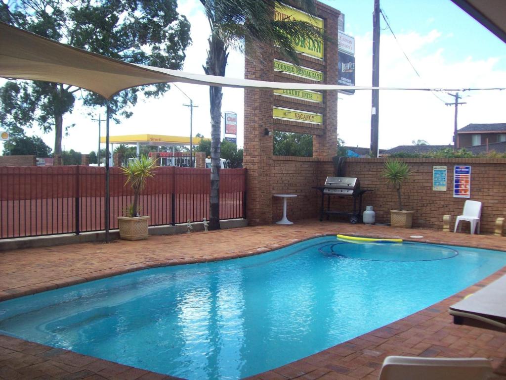 a swimming pool with an umbrella in a backyard at Cobar Town & Country Motor Inn in Cobar