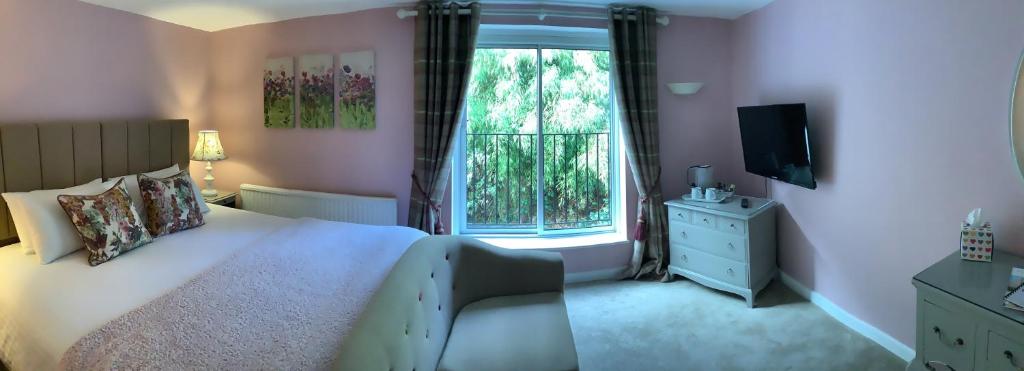 a bedroom with a large bed and a window at Combe House Hotel in Holford