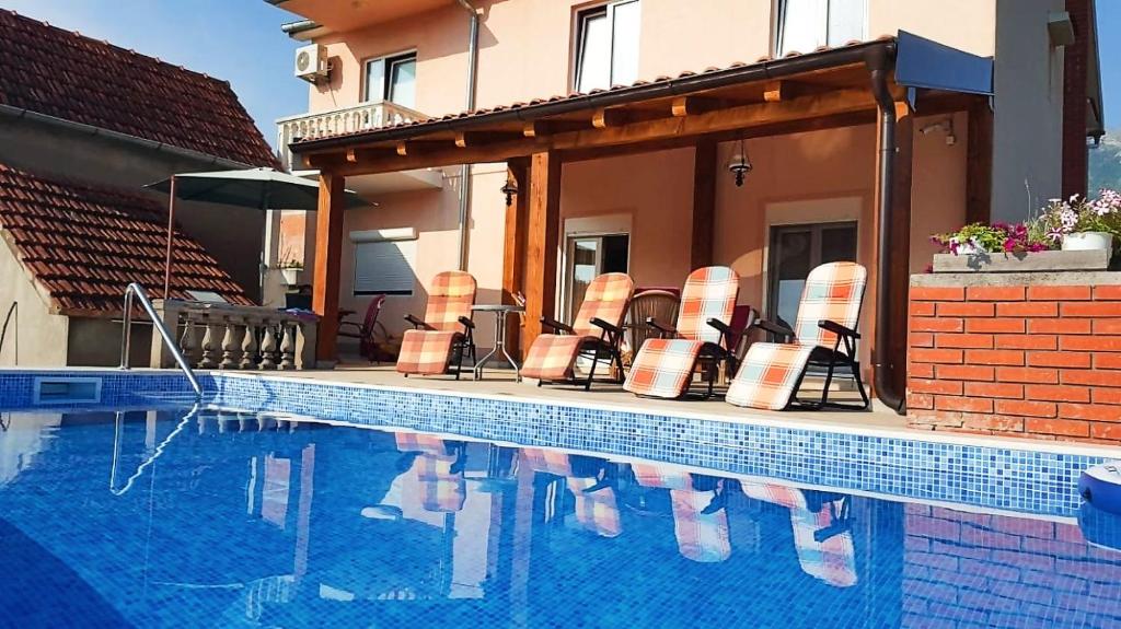 una piscina con sillas junto a una casa en Residence Lamba, en Radanovići