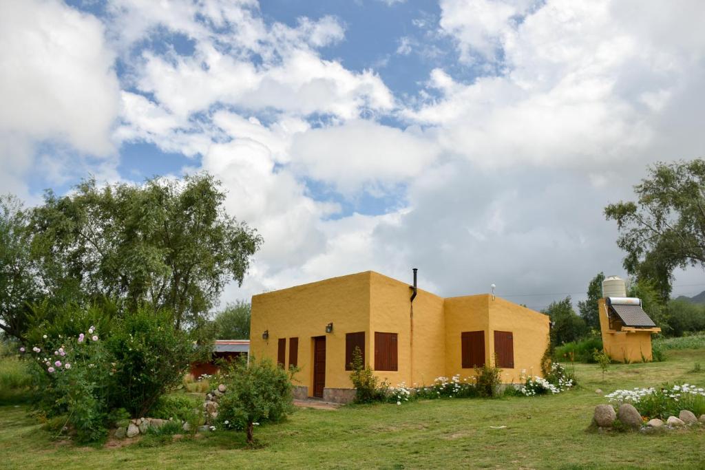 a small yellow house in a field with trees at Casa en Tafí del Valle in Tafí del Valle