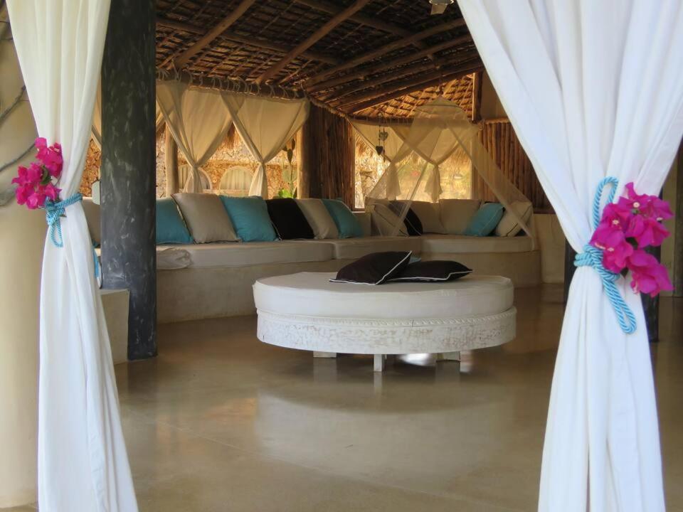 a room with a couch and a table and curtains at Fortamu - Tembo House in Watamu
