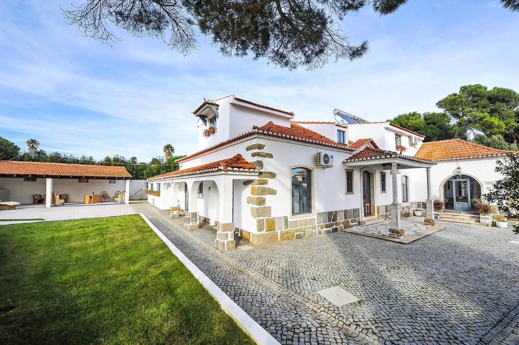 a large white house with a yard at Santo António's Guesthouse in Cascais