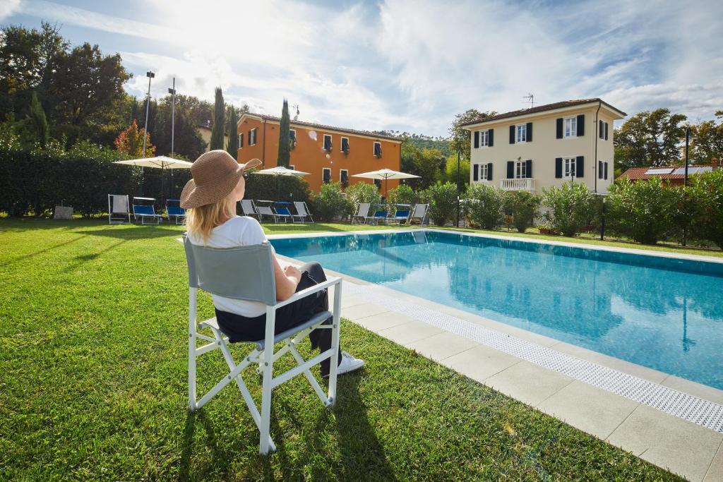 Casa da Giulio في كابانّوري: وجود امرأة جالسة على كرسي بجانب مسبح